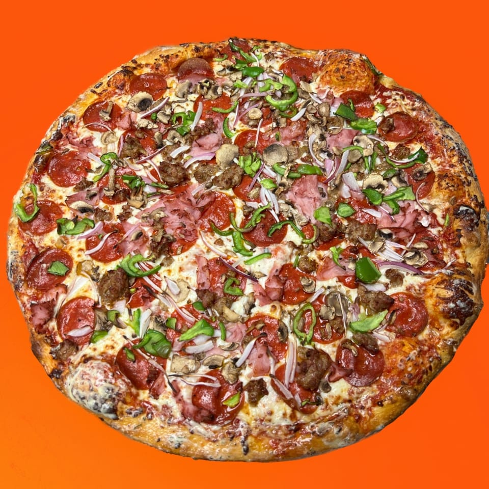 A whole pizza with pepperoni, sausage, ham, mushrooms, green peppers, and onions on an orange background.